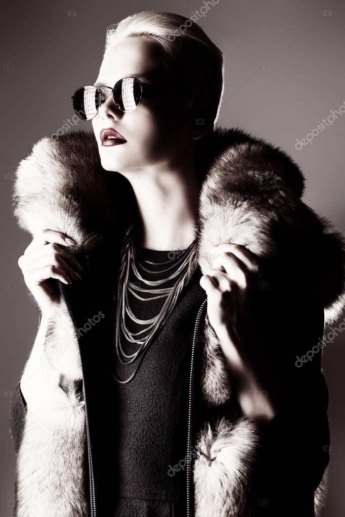 Gorgeous blonde woman posing in luxurious fur coat and a hat. Fashion, beauty. Studio shot.