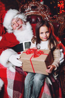 Mutlu bir genç kız Noel Baba yakınındaki bir hediye ile evde oturuyor. Mutlu Noeller ve mutlu yeni yıl.