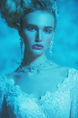 Stüdyoda mavi arka plan üzerinde poz güzel soğuk bir Bayan portresi yakından. Güzellik, kozmetik, saç modeli.