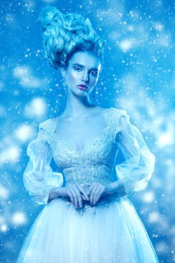 Kabarık elbise ve stüdyoda mavi arka plan üzerinde poz soğuk bir güzel Bayan portresi. Güzellik, kozmetik, saç modeli, moda.