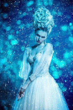 Kabarık elbise ve stüdyoda mavi arka plan üzerinde poz soğuk bir güzel Bayan portresi. Güzellik, kozmetik, saç modeli, moda.