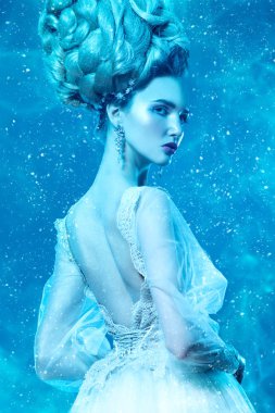 Kabarık elbise ve stüdyoda mavi arka plan üzerinde poz soğuk bir güzel Bayan portresi. Güzellik, kozmetik, saç modeli, moda.