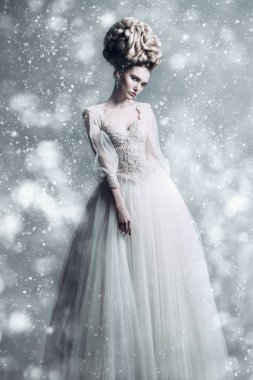 Kabarık elbise ve stüdyoda gri arka plan üzerinde poz soğuk bir güzel bayan bir tam uzunlukta portresi. Güzellik, kozmetik, saç modeli, moda.