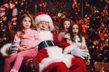 Mutlu çocuklar Noel Baba ile evde oturuyor. Mucize zamanı. Noel, yeni yıl.