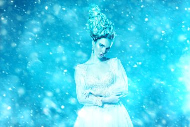 Kabarık elbise ve stüdyoda mavi arka plan üzerinde poz soğuk bir güzel Bayan portresi. Güzellik, kozmetik, saç modeli, moda.