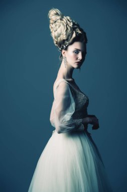 Kabarık elbise ve stüdyoda mavi arka plan üzerinde poz soğuk bir güzel Bayan portresi. Güzellik, kozmetik, saç modeli, moda.