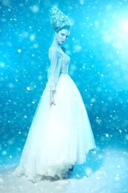 Kabarık elbise ve stüdyoda mavi arka plan üzerinde poz soğuk bir güzel bayan bir tam uzunlukta portresi. Güzellik, kozmetik, saç modeli, moda.