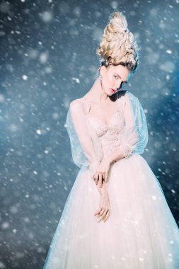 Kabarık elbise ve stüdyoda mavi arka plan üzerinde poz soğuk bir güzel Bayan portresi. Güzellik, kozmetik, saç modeli, moda.