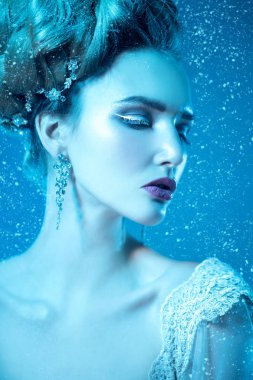 Stüdyoda mavi arka plan üzerinde poz güzel soğuk bir Bayan portresi yakından. Güzellik, kozmetik, saç modeli.