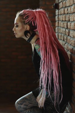 Seksi hippi kız pembe dreadlocks tuğla duvar tarafından poz ile. Güzellik, moda.