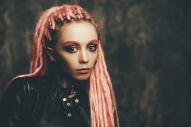 Kadın modeli pembe dreadlocks karanlık bir arka plan üzerinde poz ile çarpıcı. Son moda saç modelleri. Güzellik, moda. 