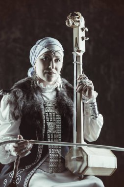 Yaşlı yerli kadın ulusal bir kostüm. Antik keman çalıyor.