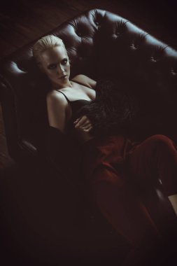 Baştan çıkarıcı kız siyah sütyen, kırmızı pantolon ve kürk ceket deri koltukta yalan. Lüks yaşam tarzı. Moda, güzellik. Stüdyo vurdu.