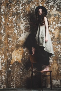 Modern giysiler stüdyoda bir sandalye üzerinde duran poz şık ergen kız. Güzellik, moda.