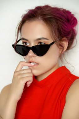 Beyaz bir arka plan üzerinde poz pin-up güneş gözlüğü oldukça pembe saçlı kız. Moda, güzellik. Optik tarzı. Gençlik stili.