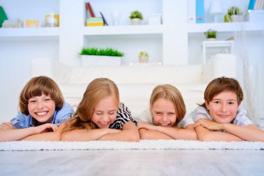 Dört komik çocuk evde yere yat ve gülmek. Çocuk kavramı.