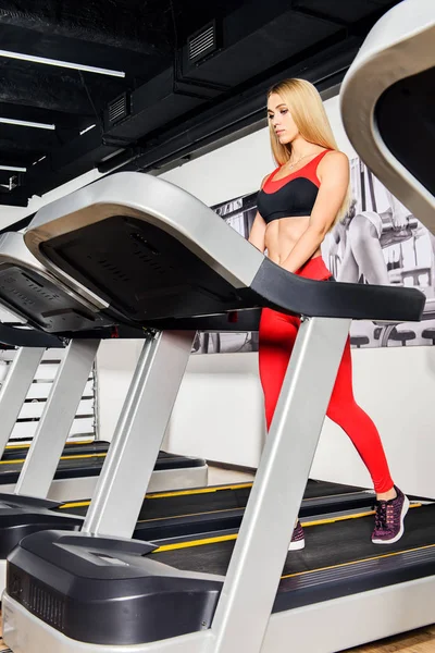 Bir spor salonu bir koşu bandı üzerinde çalışan güzel atletik genç kadın. Sağlıklı bir yaşam tarzı. Spor, fitness, vücut geliştirme.