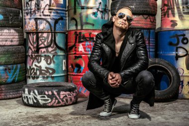 Sokakta sprey boya ile serseri bir adam portresi. Adam arka bahçesinde. Moda, alt kültür.