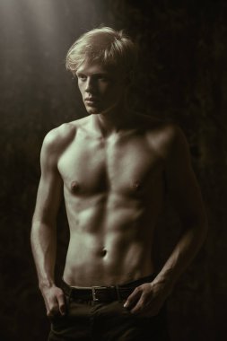 Portre gömleksiz bir gencin stüdyoda poz sarışın saçlı. Gri arka plan. Erkek Sağlığı.