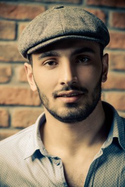 Tuğla duvar arka plan üzerinde bir kap içinde yakışıklı bir brunet adam portresi. Erkek güzelliği, moda. Erkek berber.