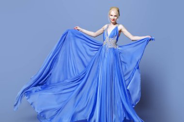 Tam uzunlukta yemyeşil etek ile zarif uzun mavi elbiseli muhteşem bir genç kadın portresi. Güzellik, moda.