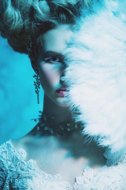 Stüdyoda mavi arka plan üzerinde poz güzel soğuk bir Bayan portresi yakından. Güzellik, kozmetik, saç modeli.