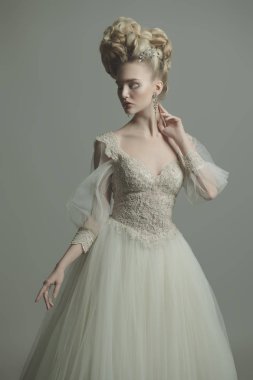 Kabarık elbise ve stüdyoda gri arka plan üzerinde poz soğuk bir güzel Bayan portresi. Güzellik, kozmetik, saç modeli, moda.