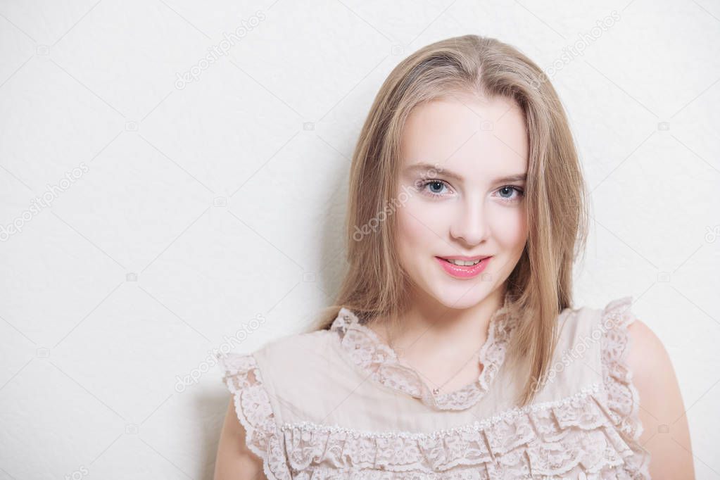 Portrait of a cute girl teenager in standing lace dress and leaning on the wall in the room. Beauty, fashion.