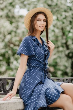 Hasır şapkalı güzel kız bir çiçek bahçesinde poz. Güzellik, moda.