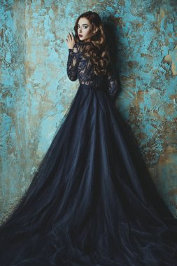 A full length portrait of a beautiful brunette ladys on grunge background. Evening dress. Fashion, beauty.