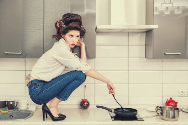 Günlük giysiler ve curlers çekici bir kız ayarla ve yemek mutfak tezgah üzerinde duruyor. Moda ev atış. Tam uzunlukta portre. 