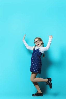 Mutlu kız mavi arka plan üzerinde poz. Mutlu çocukluk. Bahar tatil.