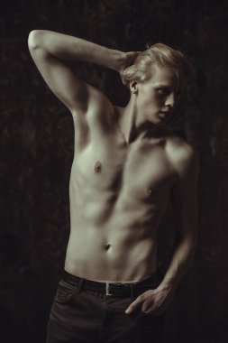 Portre gömleksiz bir gencin stüdyoda poz sarışın saçlı. Gri arka plan. Erkek Sağlığı.