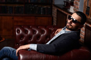 Deri koltuk üzerinde seksi yakışıklı bir adam portresi. Moda vurdu. Erkek güzelliği, moda. Erkek Berber Dükkanı, saç modeli.