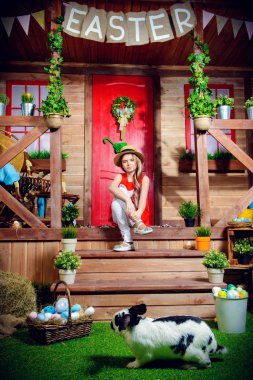 Paskalya tatili. Mutlu kız verandada bir köy evi ve tavşan çim üzerinde çalışan poz. Paskalya süsleri. 