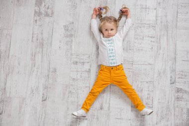 Neşeli bir kız yerde yatıyor. Çocuklar için moda.