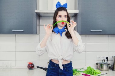 Günlük giysiler içinde çekici bir kız mutfakta yemek pişiriyor. Mutfakta yemek pişirmek. Gastronomik konsept.