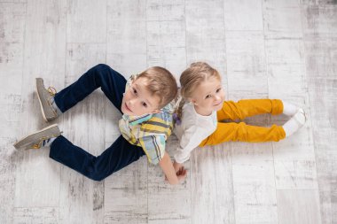 İki neşeli çocuklar katta oturuyor. Çocuklar için moda.