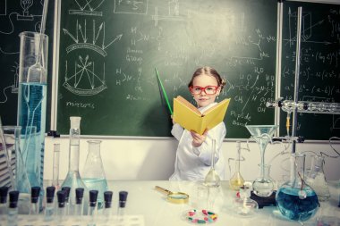 Zeki kız öğrenci tarafından açık bir kitap ile bir kara tahta kimya dersi üzerinde duruyor. Eğitim kavramı.