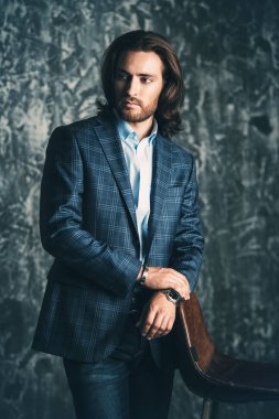 Vogue shot stüdyoda bir koltuk ile poz yakışıklı bir adam. Mobilya ve iç. Erkek güzellik, moda.