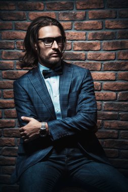 Modern bir iç bir sandalyede oturan şık elbiseli genç adam heybetli. Moda. İş.