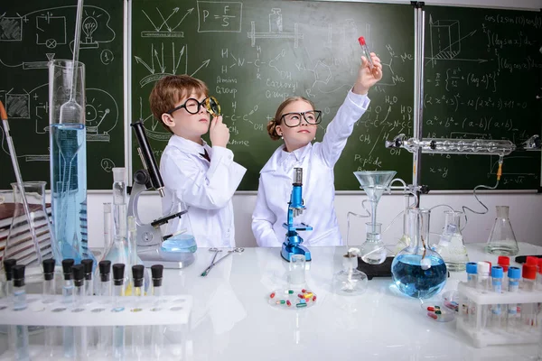 İki çocuk bilim adamları deneyler laboratuvarda yapma. Eğitim kavramı. Erken çocuk gelişimi.