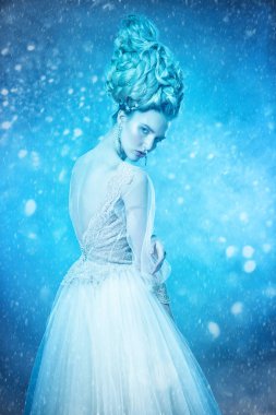 Kabarık elbise ve stüdyoda mavi arka plan üzerinde poz soğuk bir güzel Bayan portresi. Güzellik, kozmetik, saç modeli, moda.