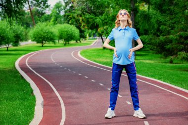 Hamile kadın parkta egzersizleri yapıyor. Gebelik. Sağlıklı yaşam tarzı.