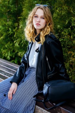 Bir bankta oturan genç bir kadın. Güzellik, şehir moda. Rahat tarzı.