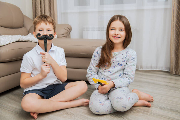 Cute girl and boy are having fun and playing games at home. Childhood. Kid's fashion 