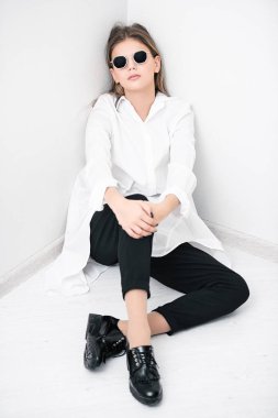 Sevimli kız genç odası katta oturan güneş gözlüğü ile portresi. Modern bir genç nesil için gözlük. Güzellik, moda.