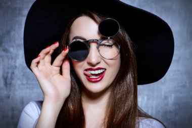 Yakın çekim yuvarlak güneş gözlüğü ve şapka giyen bir hippi kız portresi. Güzellik, kozmetik.