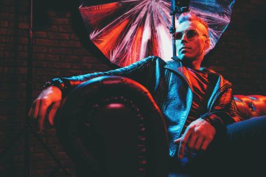 Çılgın disko adam kanepede oturuyor. Parti, disko. Renkli ışık.