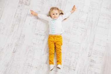 Neşeli bir kız yerde yatıyor. Çocuklar için moda.